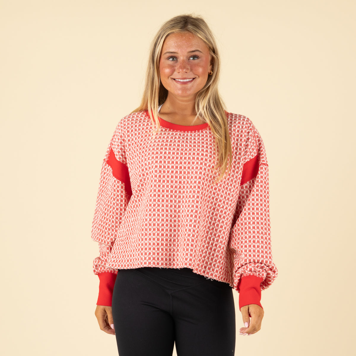 Woman wearing a red and white patterned top with an open back on a beige background