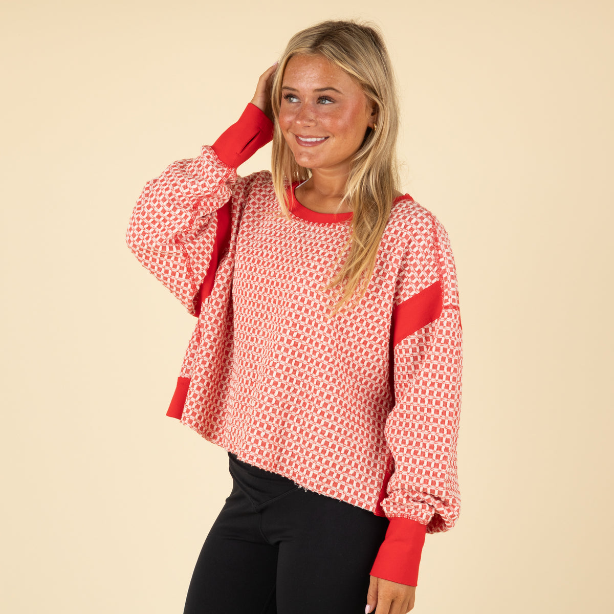 Woman wearing a red and white patterned top with an open back on a beige background