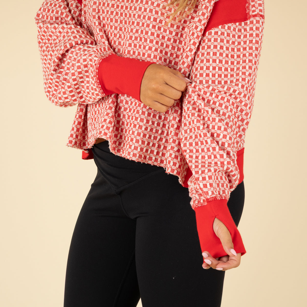 Woman wearing a red and white patterned top with an open back on a beige background