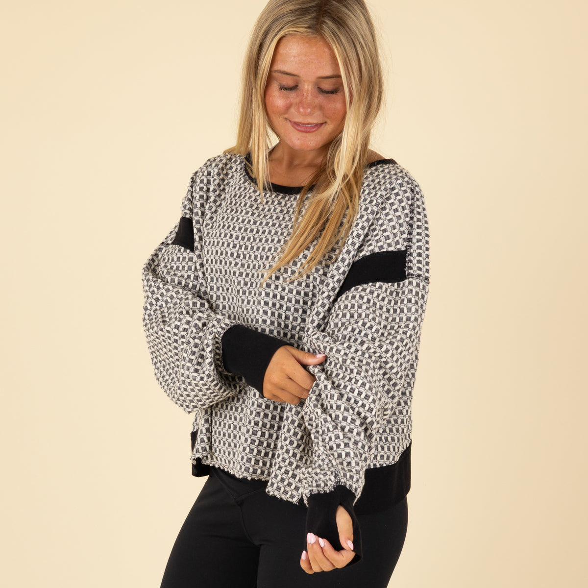 Black and white geometric patterned long-sleeve top with black cuffs and neckline, shown from the front with a loose fit.