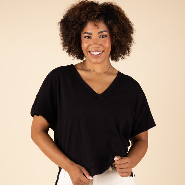  Woman wearing a black V-neck shirt against a beige background