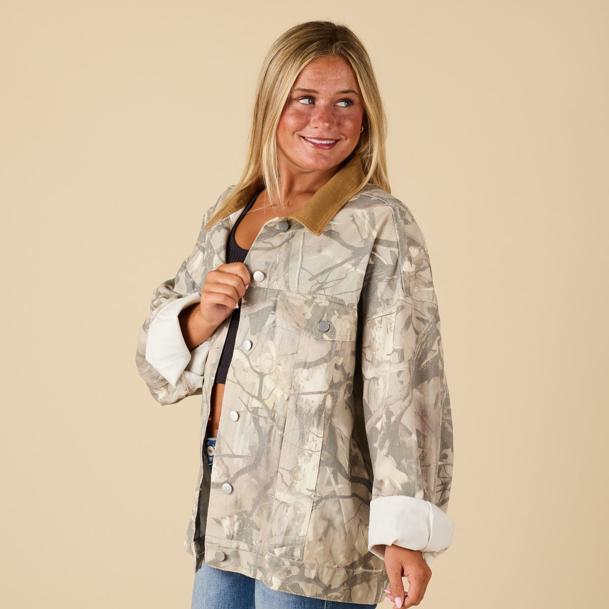 Side angle of women’s oversized camo jacket with corduroy collar and rolled cuffs, styled with jeans.