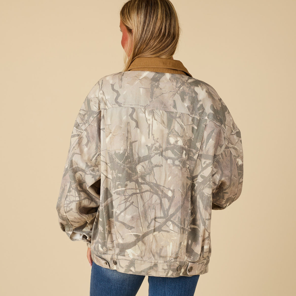Back view of women’s oversized camo jacket with light neutral camo print and brown corduroy collar.