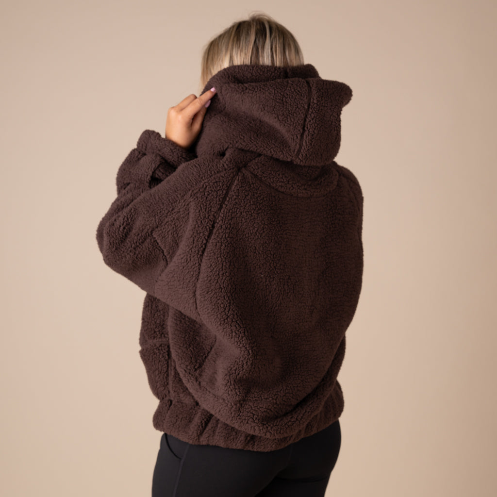 Person wearing a brown fleece jacket against a beige background