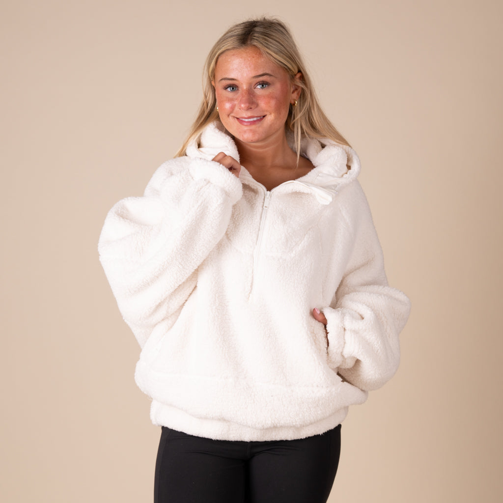 Woman wearing a white fleece jacket against a beige background