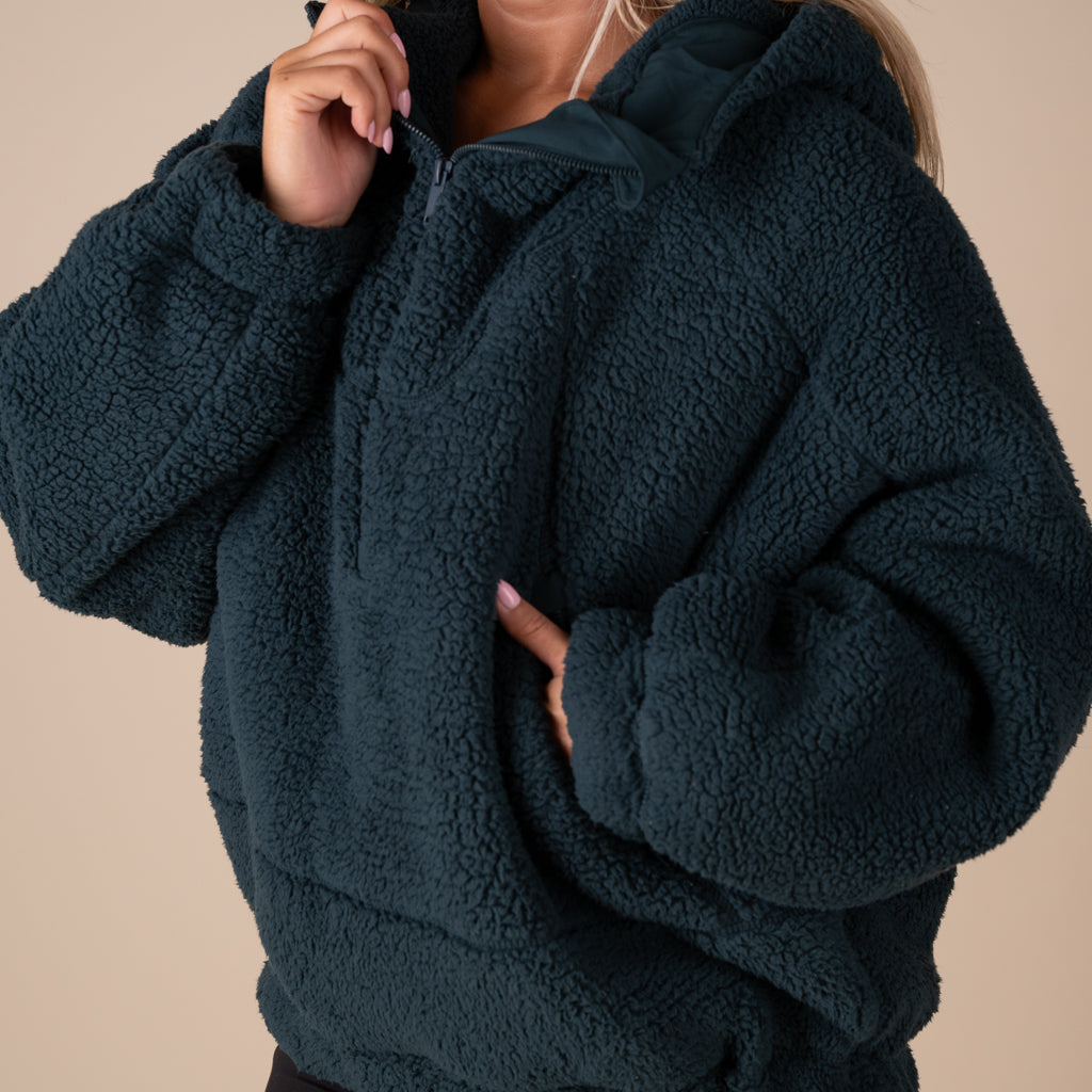 Dark green fleece jacket worn by a person on a beige background