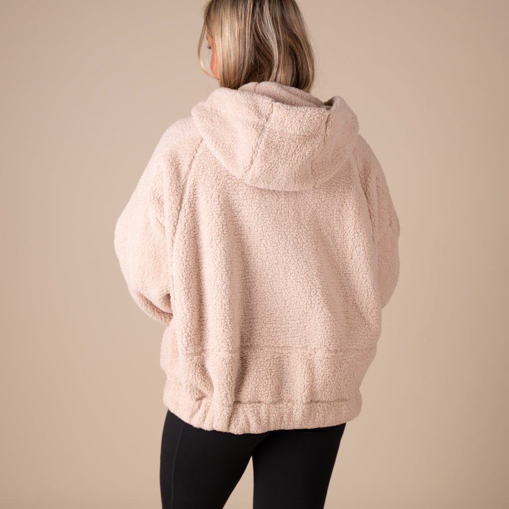 Person wearing a beige fleece jacket on a beige background