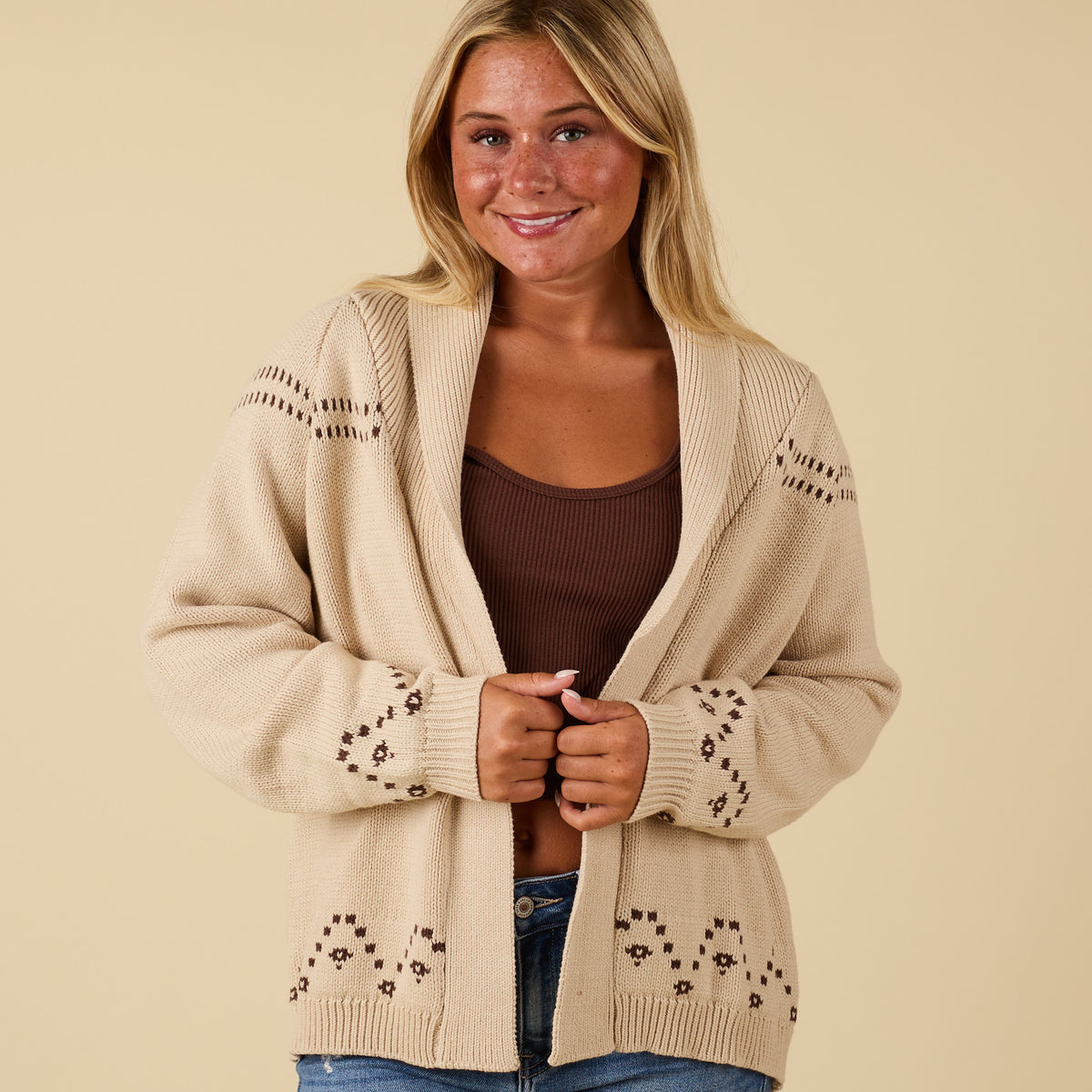 Front view of ivory cardigan with open front, fold-over collar, and patterned sleeve accents.