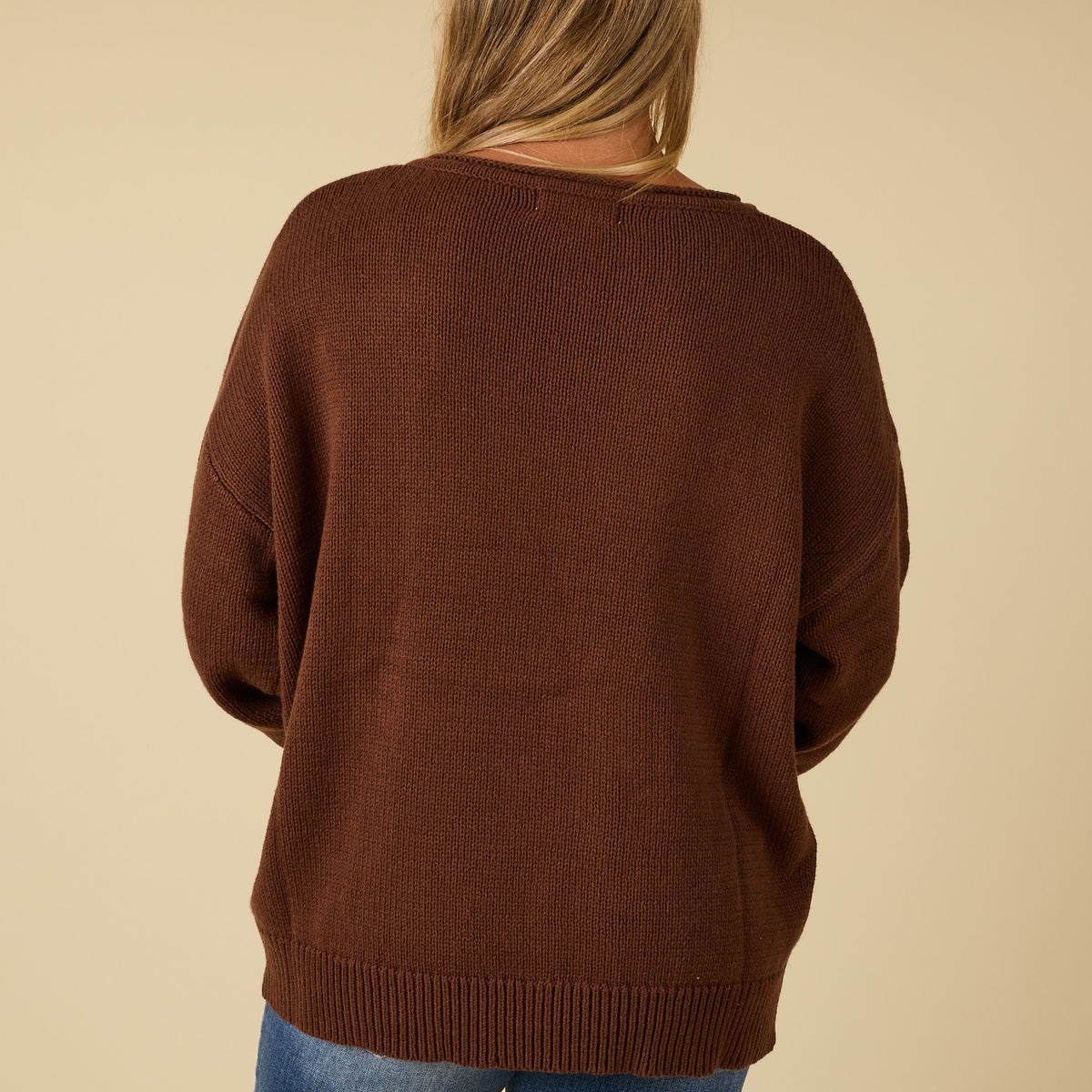 Back view of brown knit sweater with relaxed fit and ribbed hem.