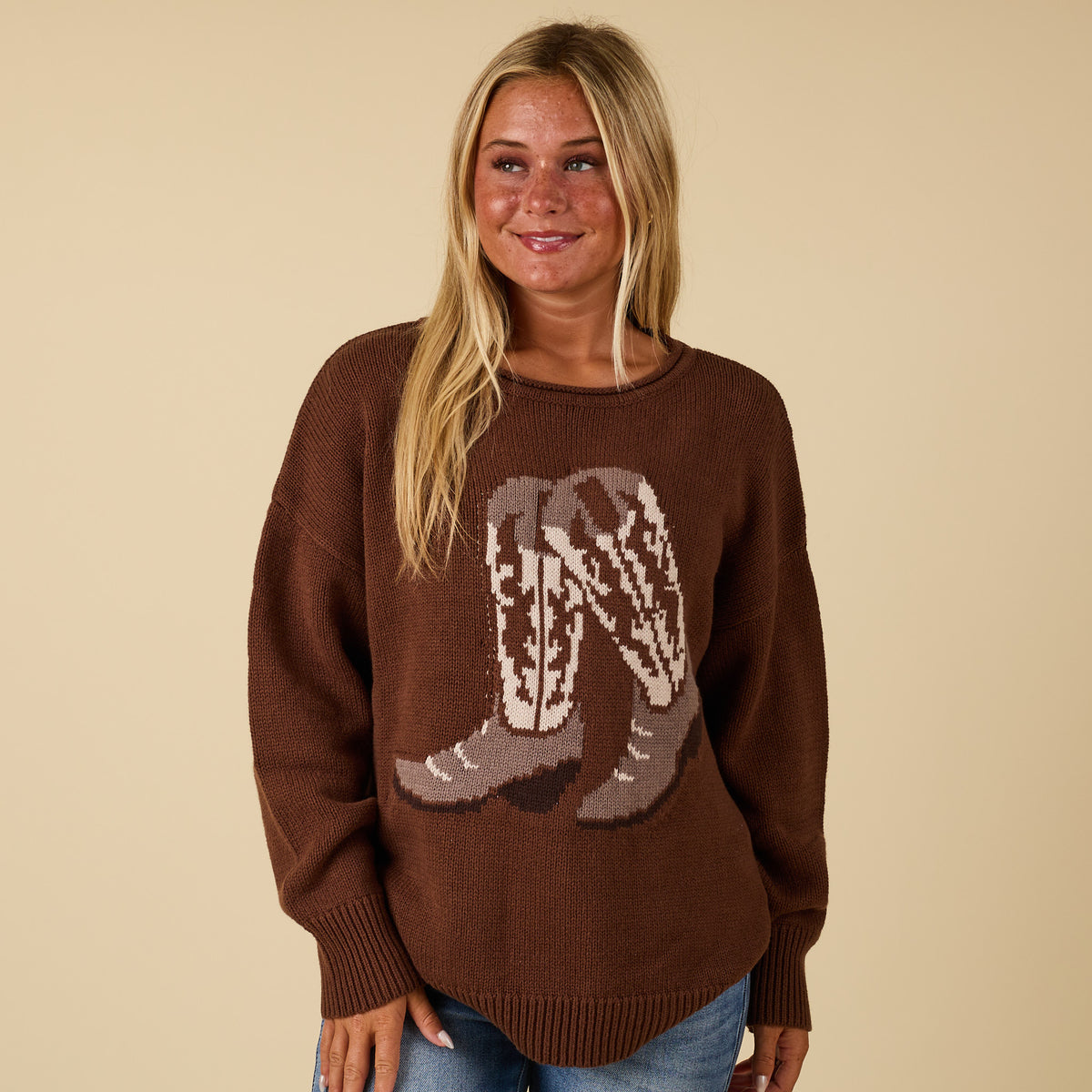 Brown knit sweater with cowboy boot graphic, relaxed fit, worn by model with jeans.