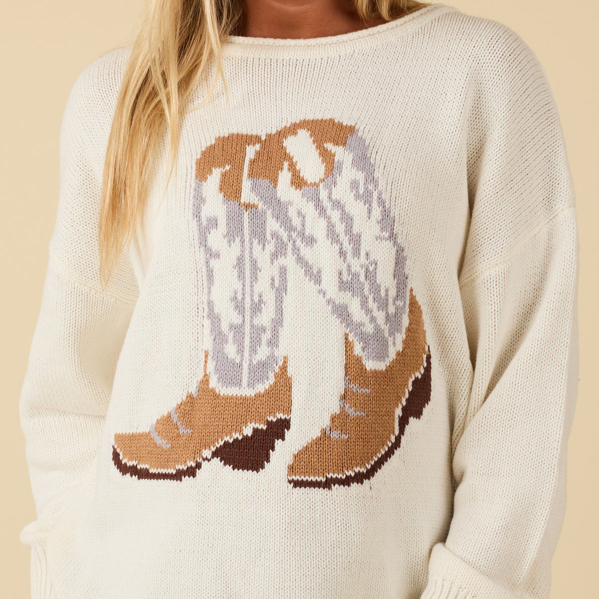 Ivory knit sweater with large cowboy boot graphic in tan, gray, and brown on the front.