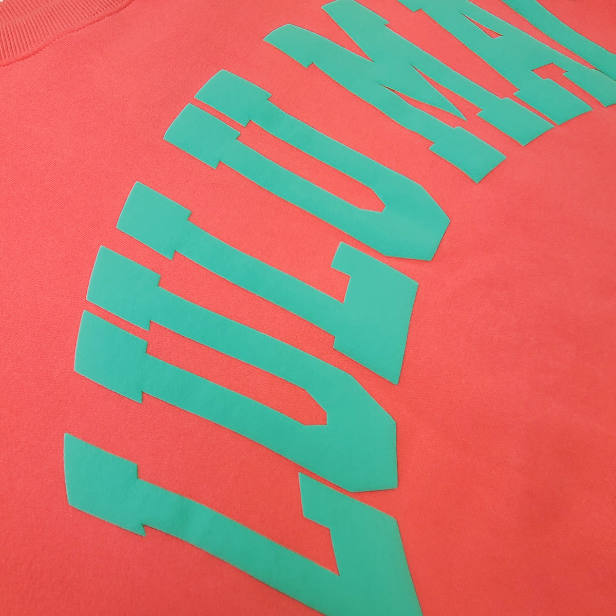 Close up of Lulu mac arch letters on a coral sweatshirt.