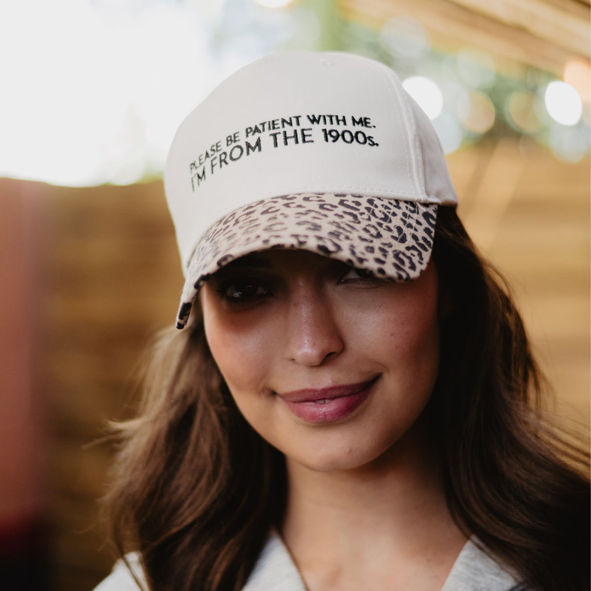 Person wearing a cap with text and leopard print visor