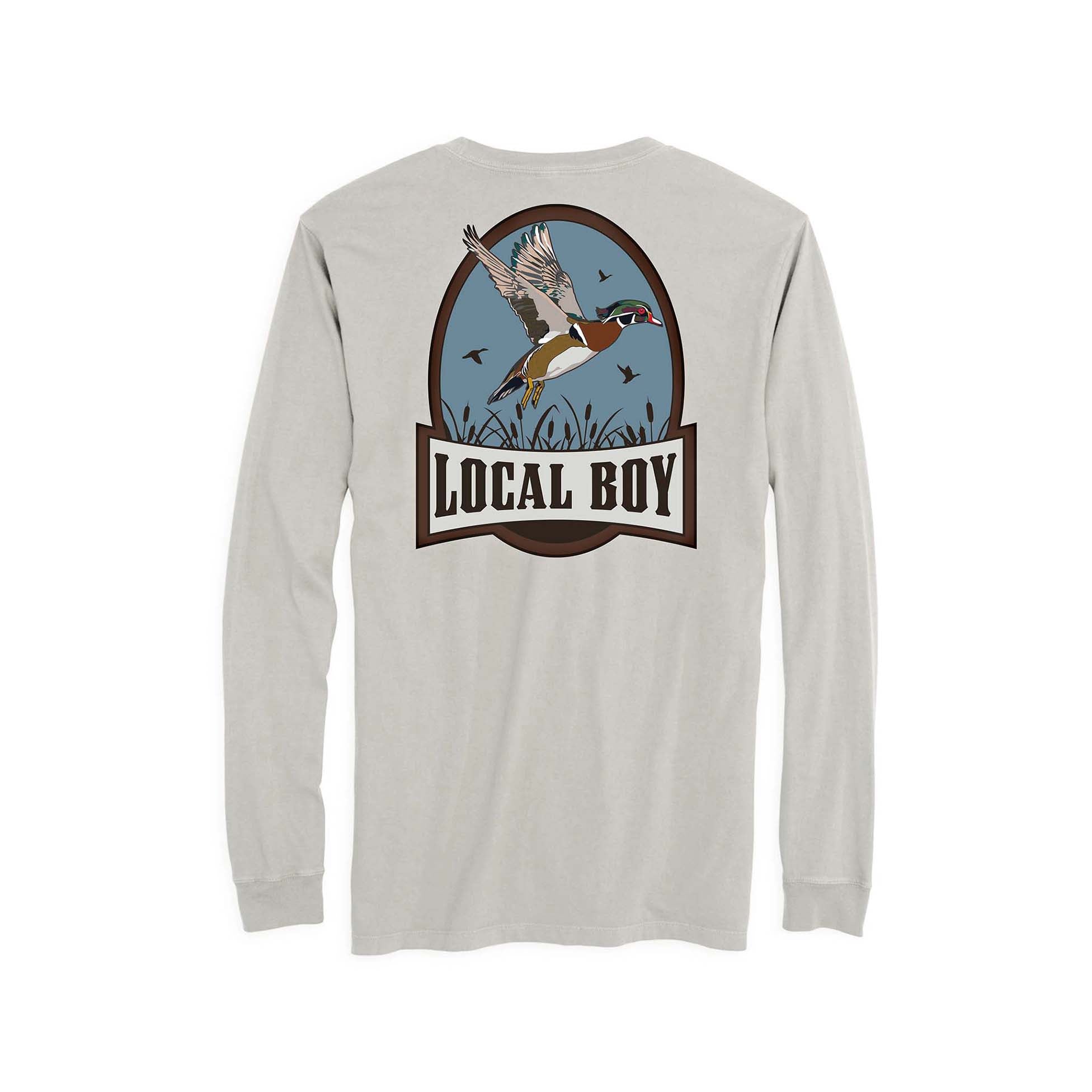Youth silver long-sleeve tee featuring a large back graphic of a flying mallard over marsh grass with “LOCAL BOY” text in a brown oval frame.