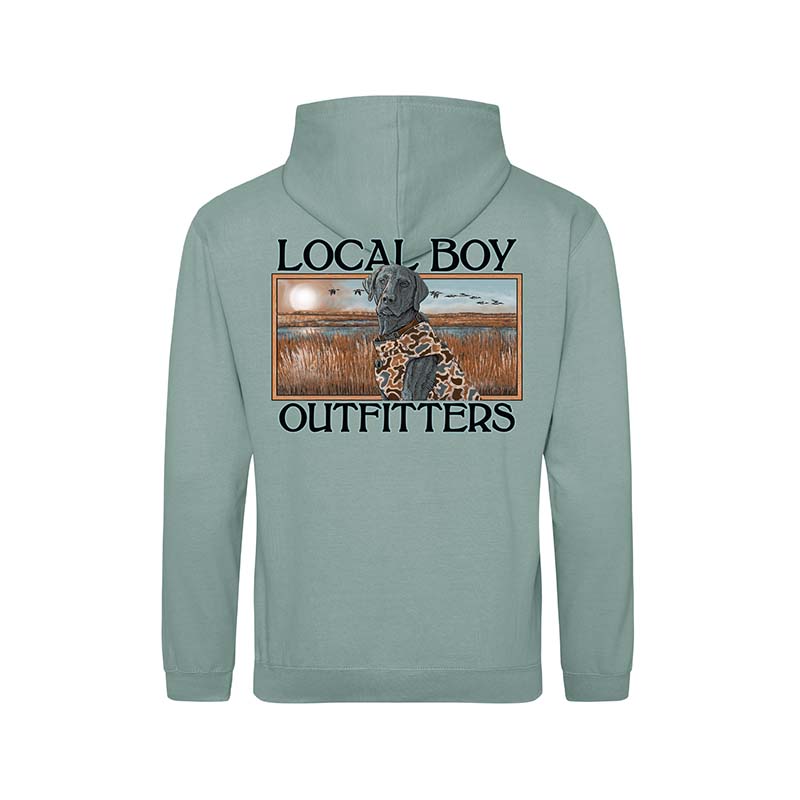 Back view of a dusty green Local Boy Outfitters hoodie featuring a lab in camo gear sitting in marsh grass with sunset and flying ducks, framed by bold logo text.