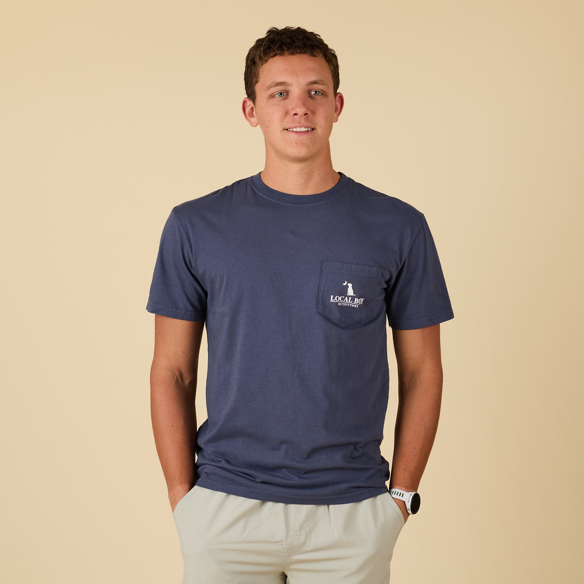 Man wearing a navy blue t-shirt with a logo on a beige background