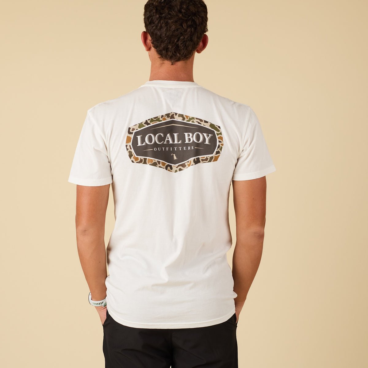 Back view of white Local Boy Outfitters t-shirt with large camo-framed logo graphic.