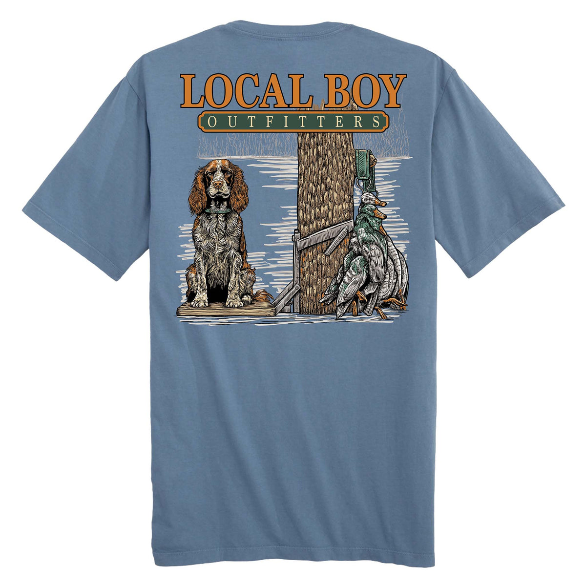 Back view of slate blue short sleeve t-shirt with Local Boy Outfitters logo, retriever sitting by tree, shotgun, and hanging ducks.