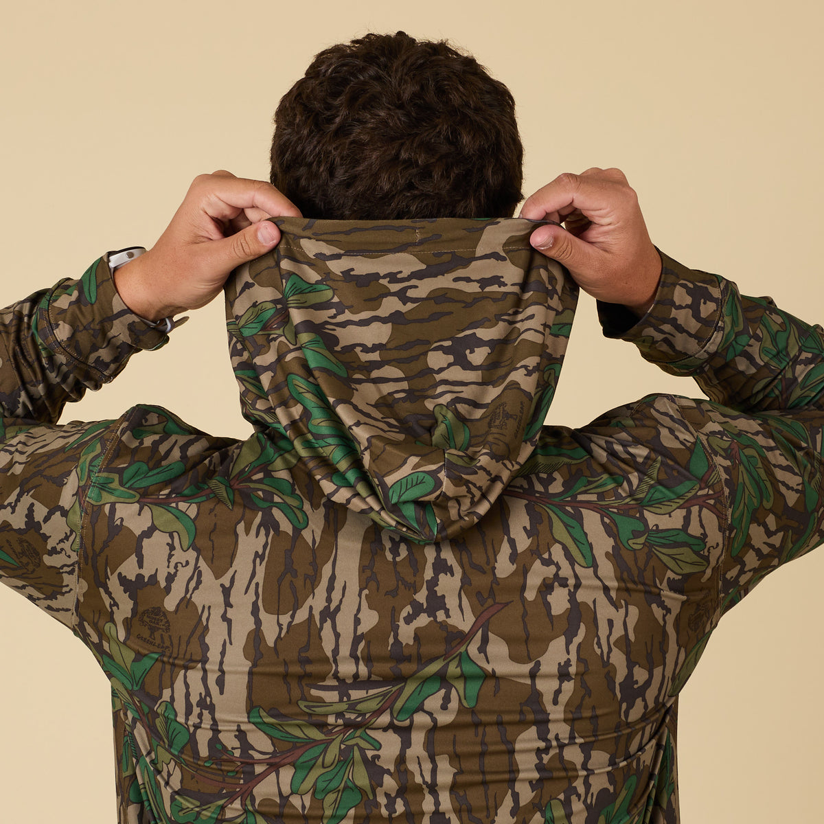 Person wearing a camouflage performance hoodie with a neutral background