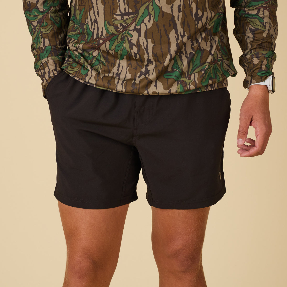 Front view of man wearing a camo performance hoodie and black shorts.