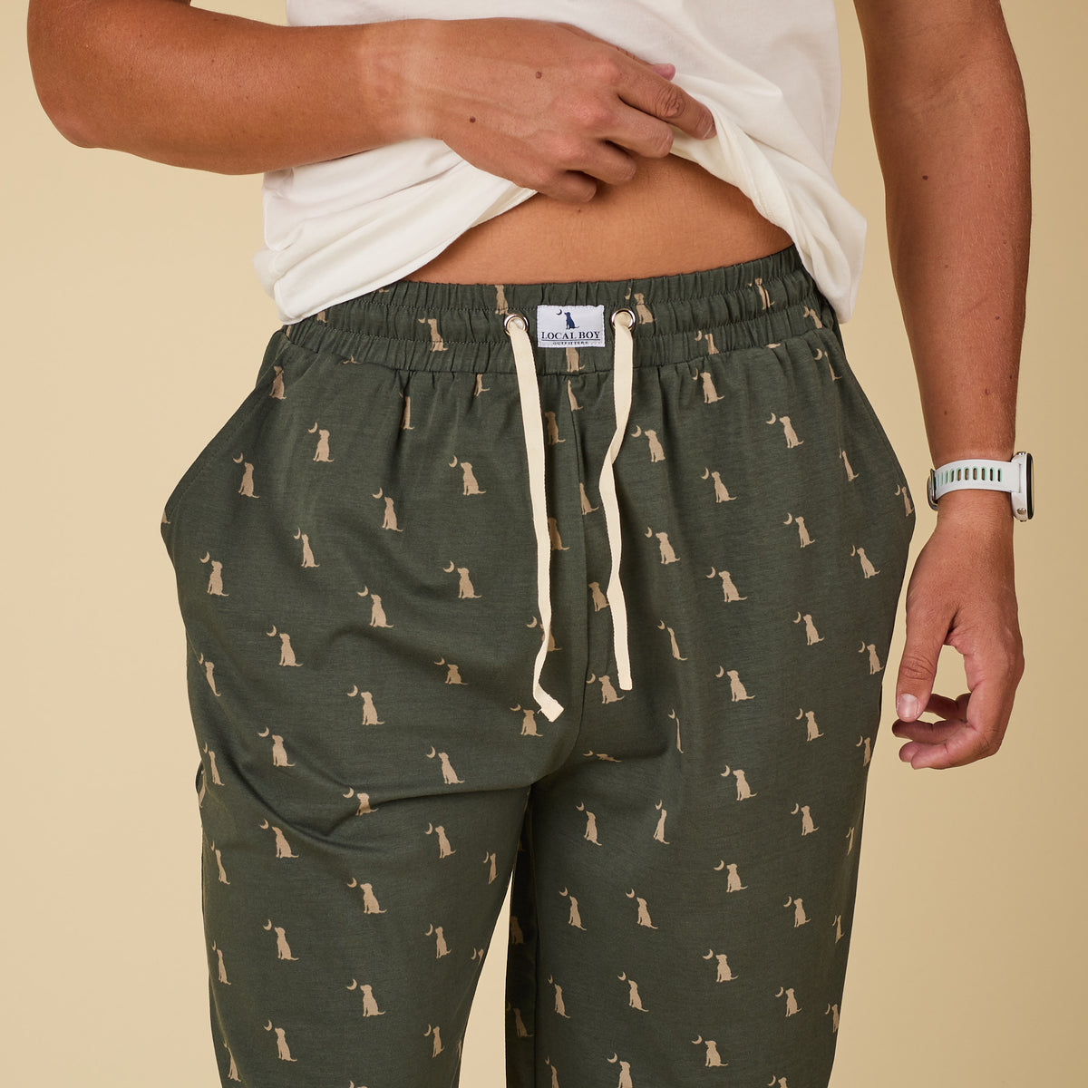 Person wearing green pants with dog pattern and white shirt on beige background