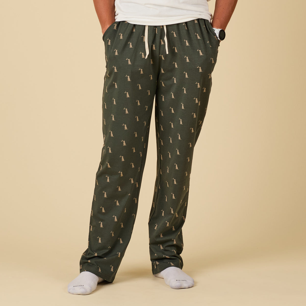 Person wearing green pajama pants with a pattern on a beige background