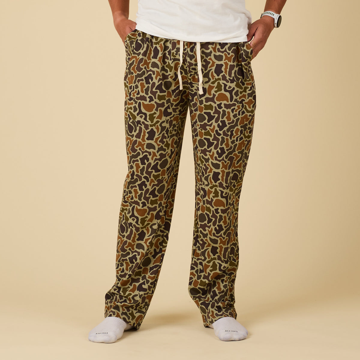 Person wearing camo print pajama pants on a beige background