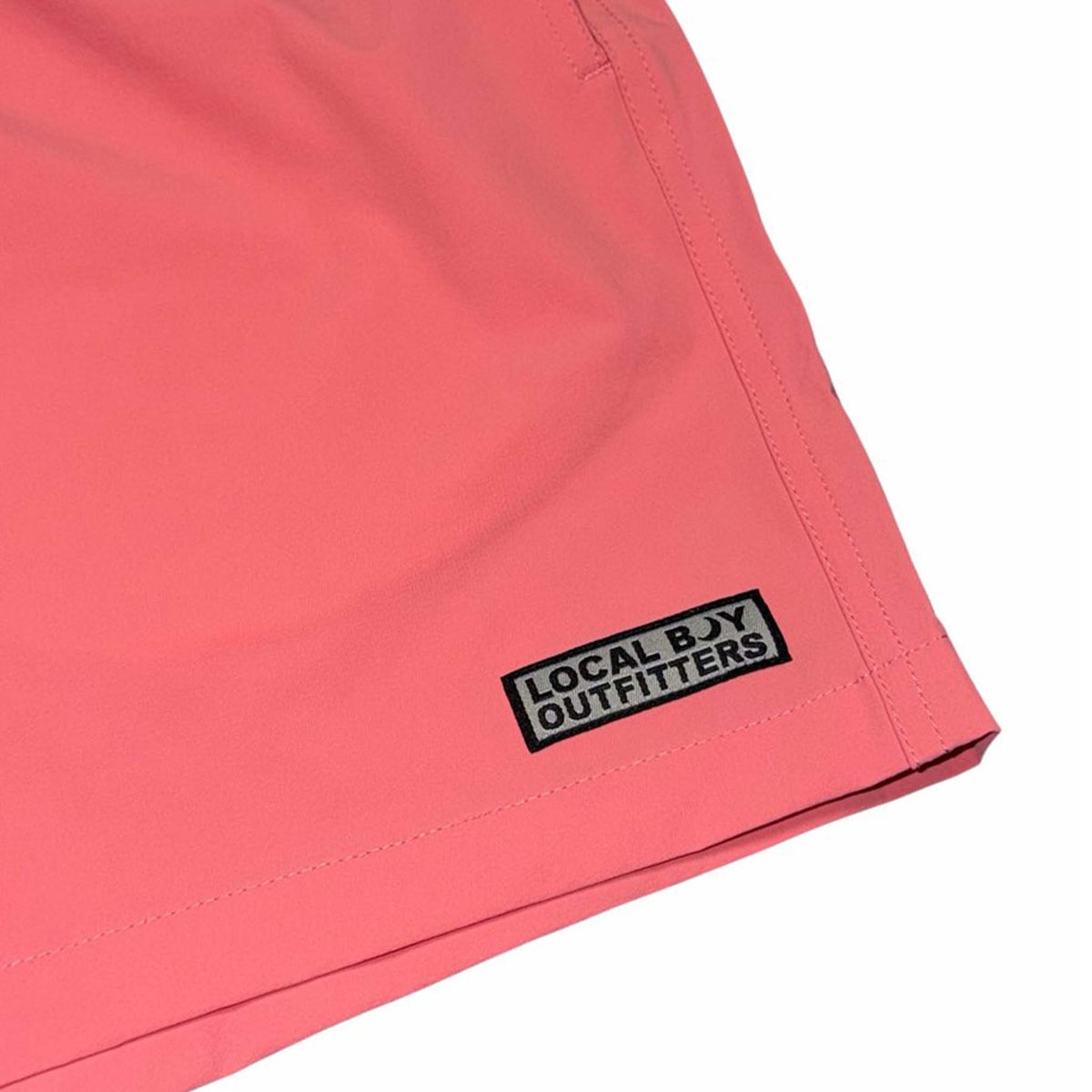 close up of logo on left leg of Local Boy Outfitters Men's Bayview swim shorts in bright coral
