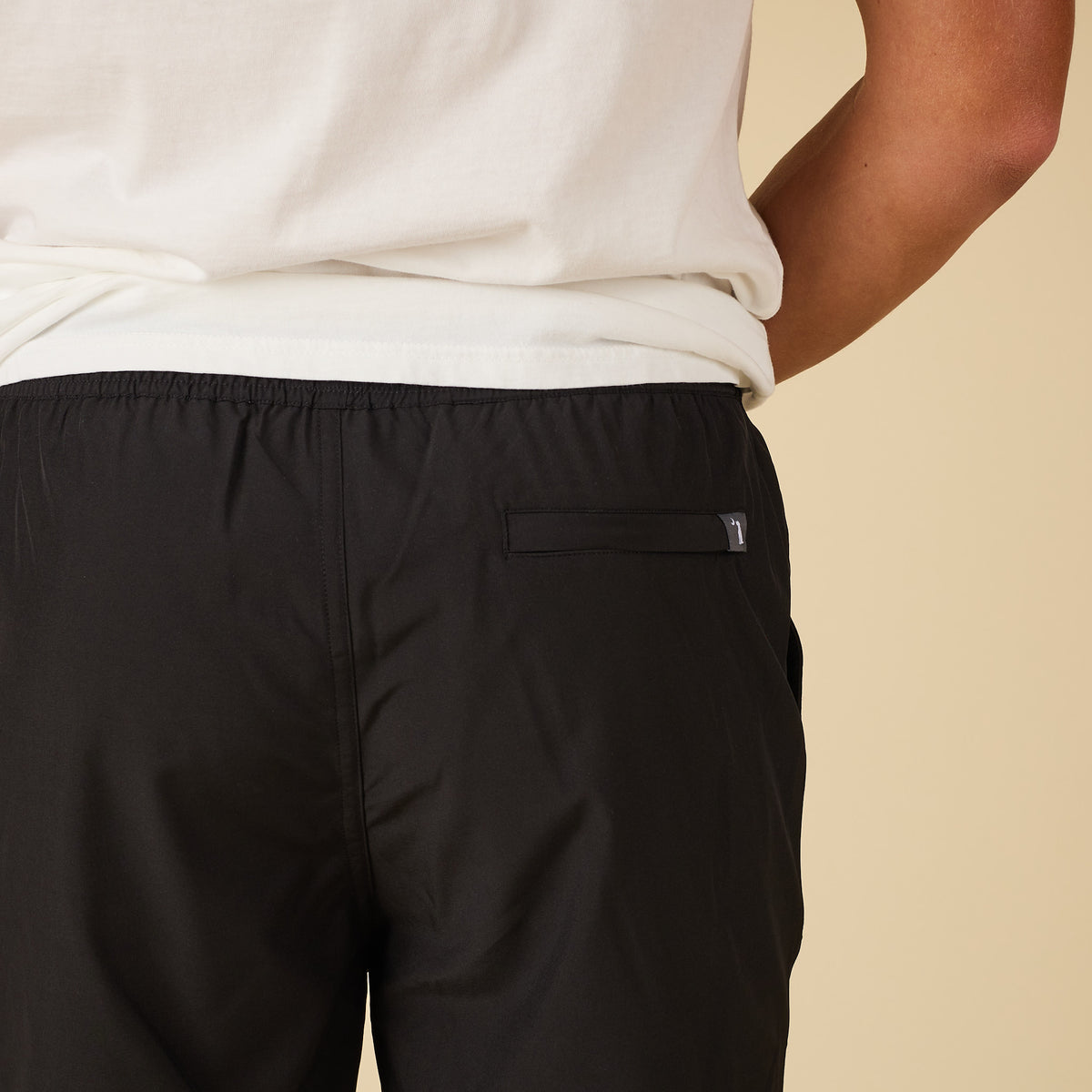 Black pants with a brand logo on a beige background