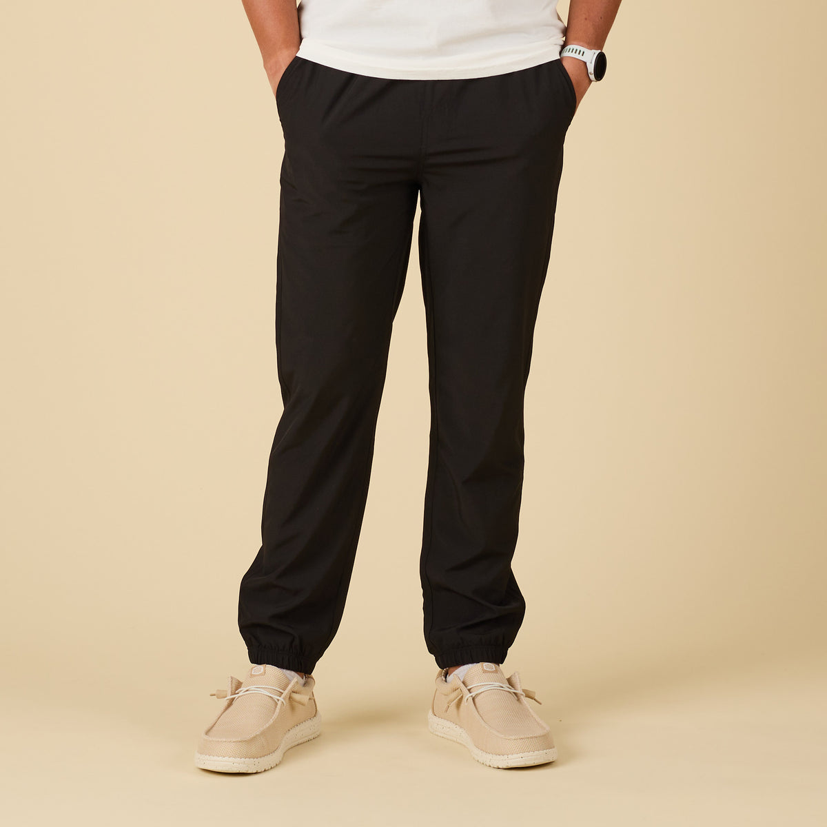 Person wearing black pants and beige shoes on a beige background