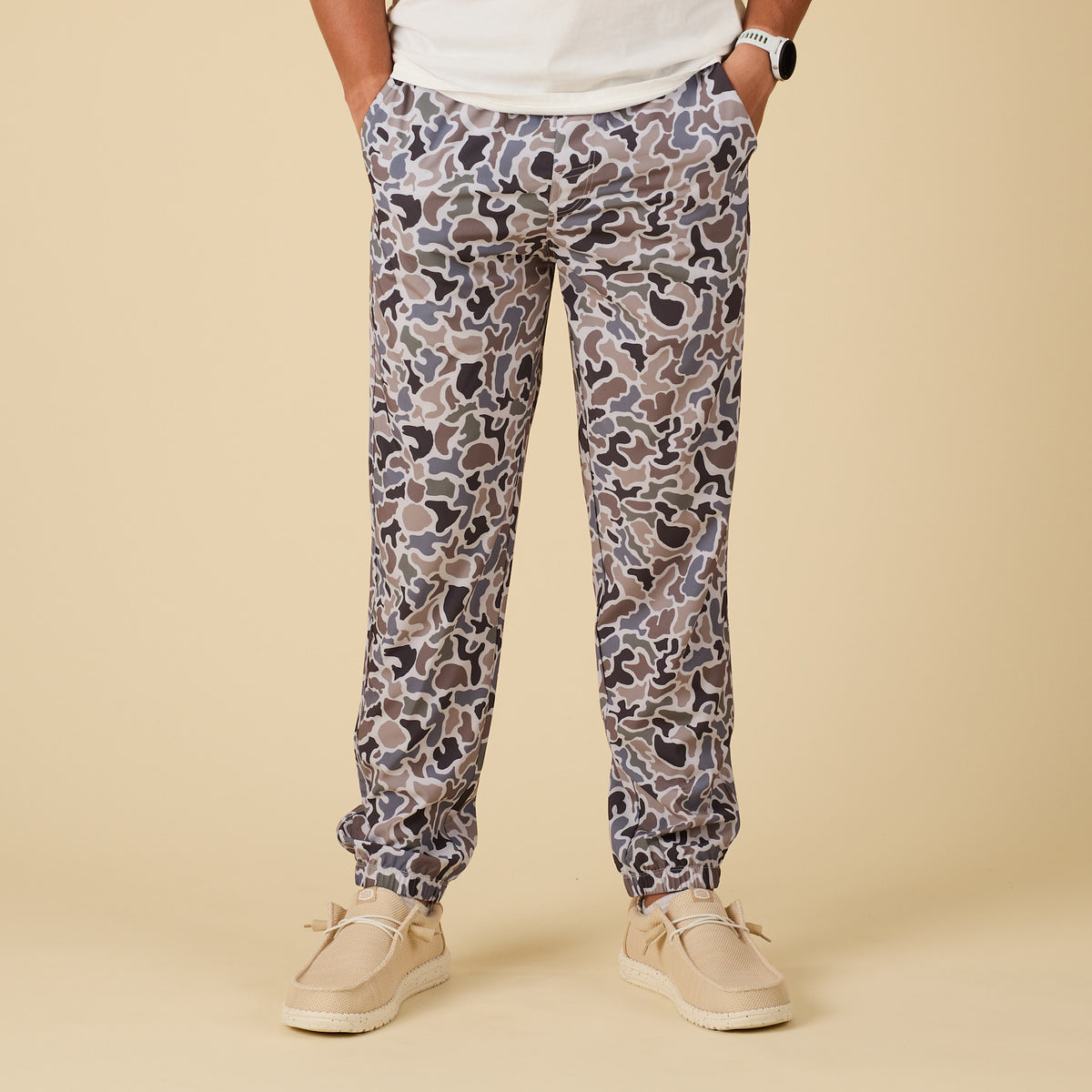 Person wearing camo pants on a beige background