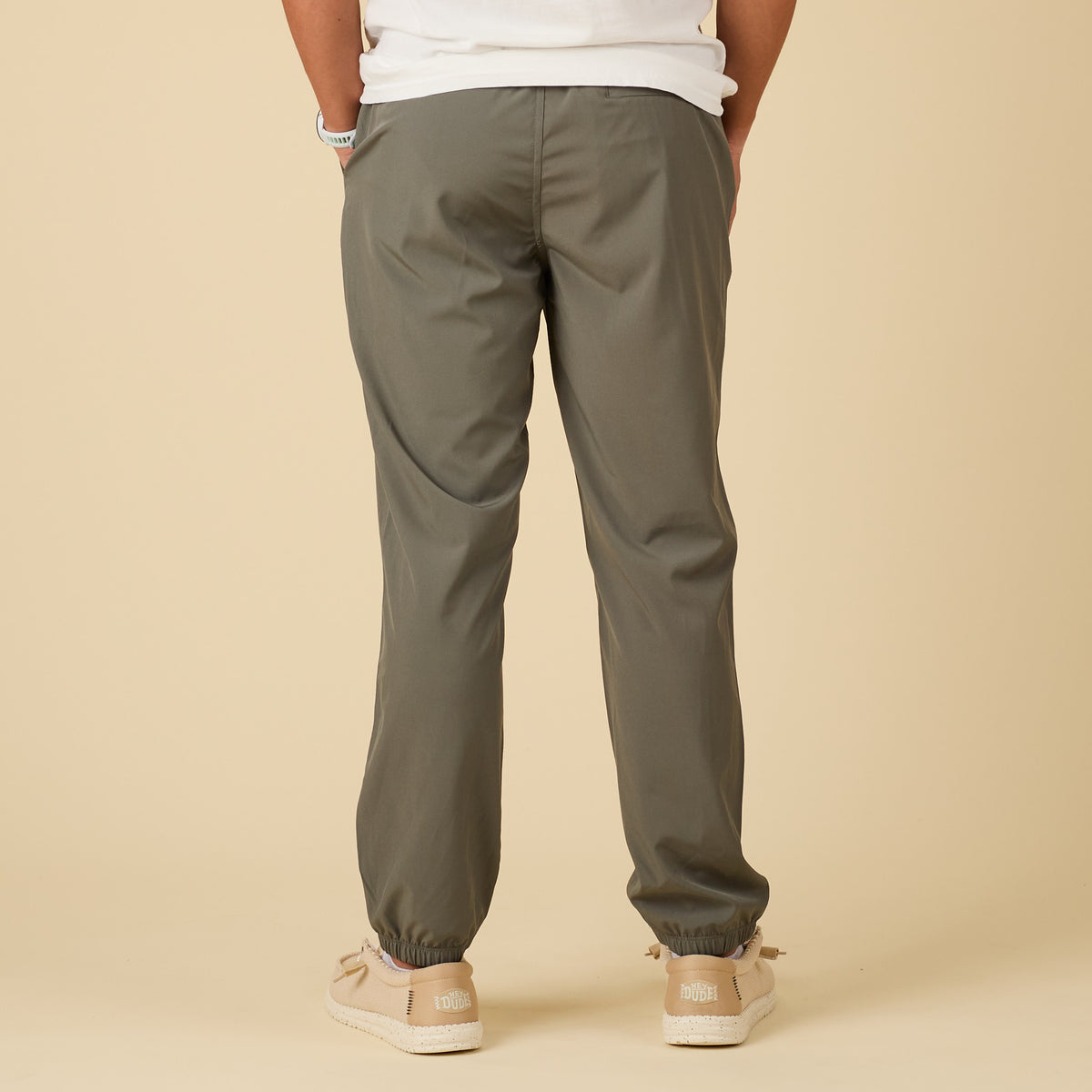 Person wearing olive green pants on a beige background