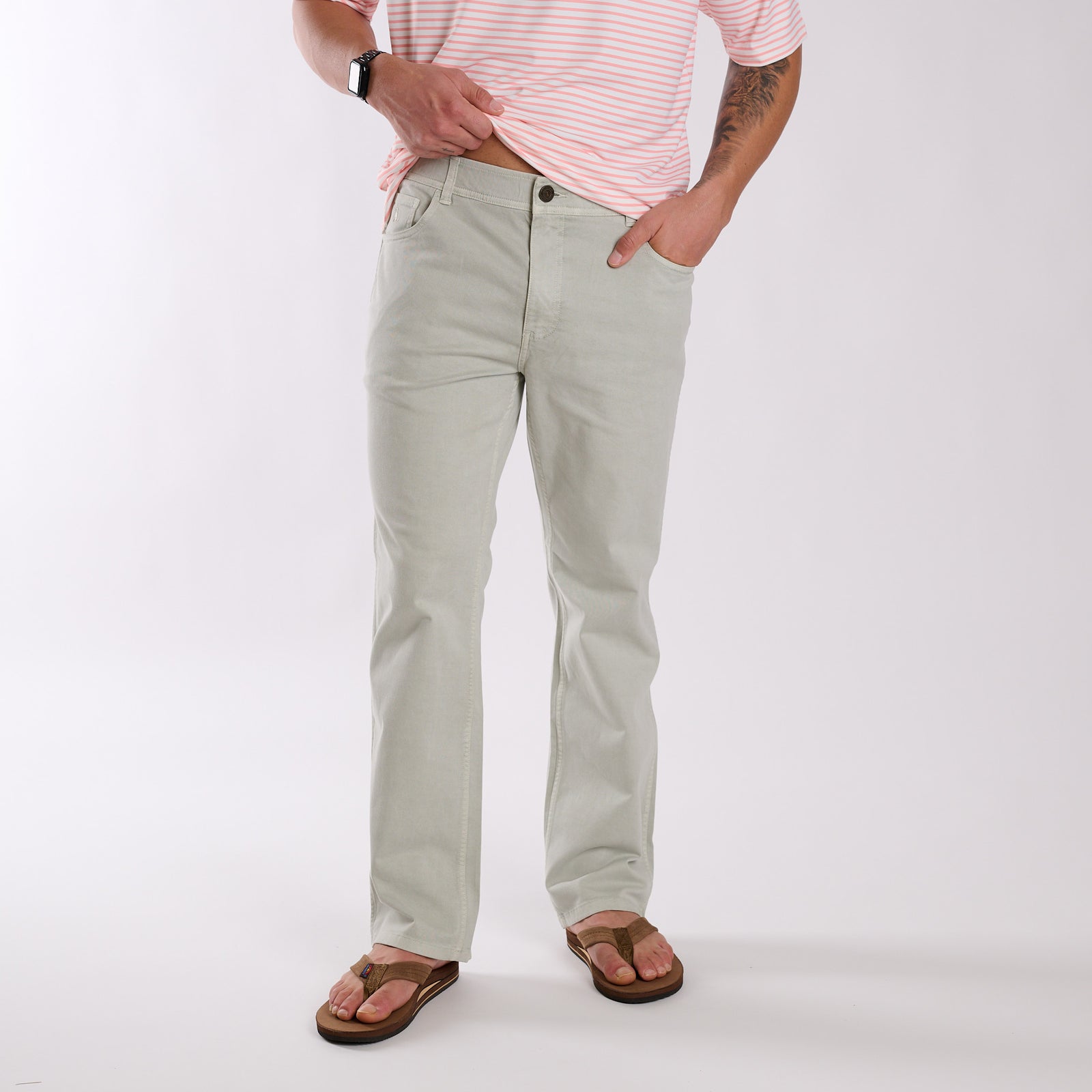 Person wearing light gray pants and a pink striped shirt on a white background