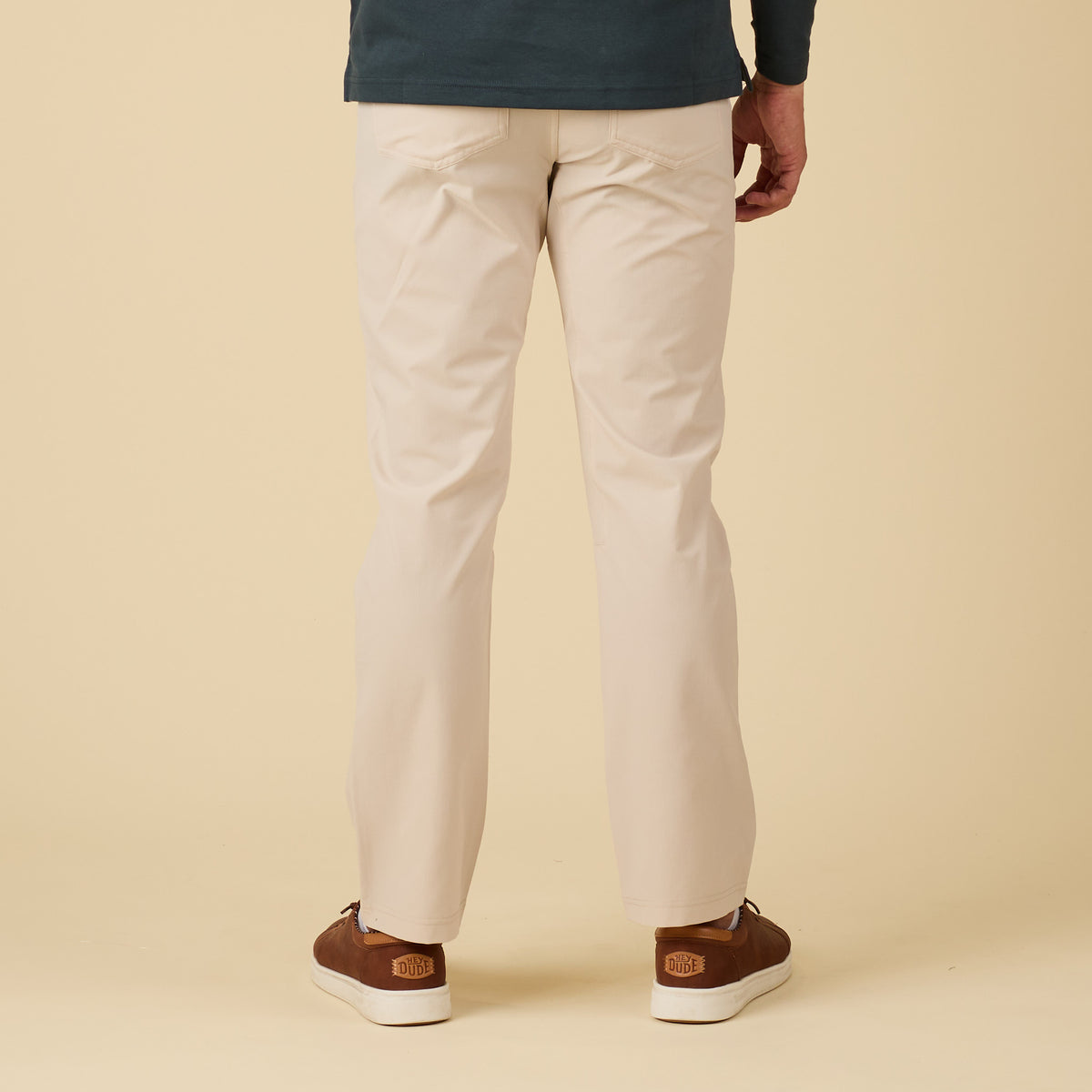 Person wearing beige pants and brown shoes on a beige background