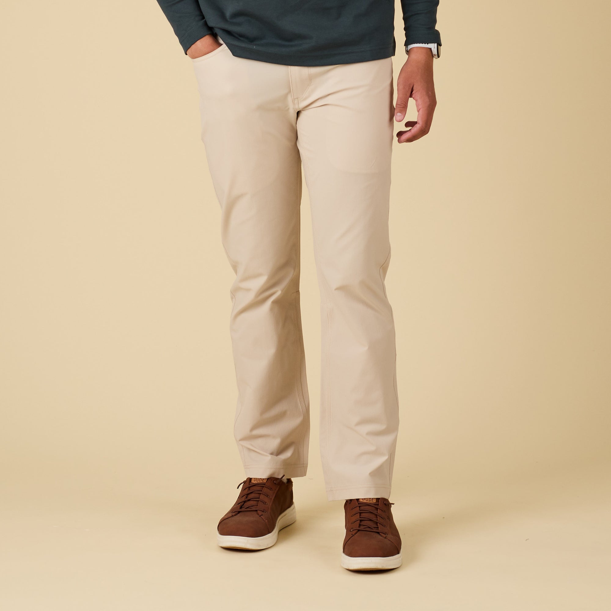 Person wearing beige pants and brown shoes on a beige background