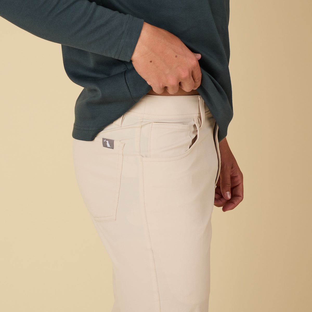 Person wearing beige pants with a plain background