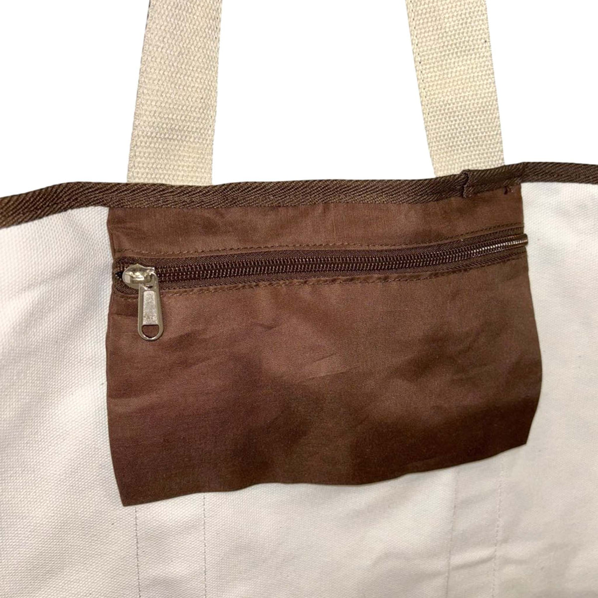 Interior view of tote bag showing brown zippered pocket with white lining.