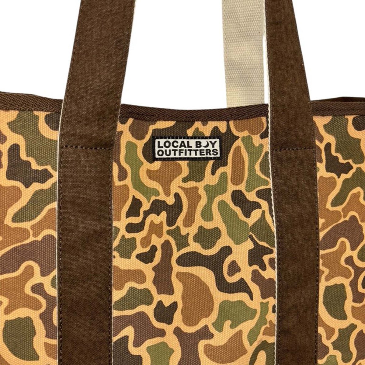 Close-up of Local Boy Outfitters logo patch on camouflage tote bag front.