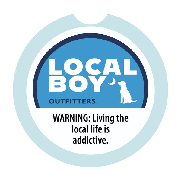 Local Boy Outfitters round car coaster with blue and white logo design and the phrase “Warning: Living the local life is addictive.” printed on the front.
