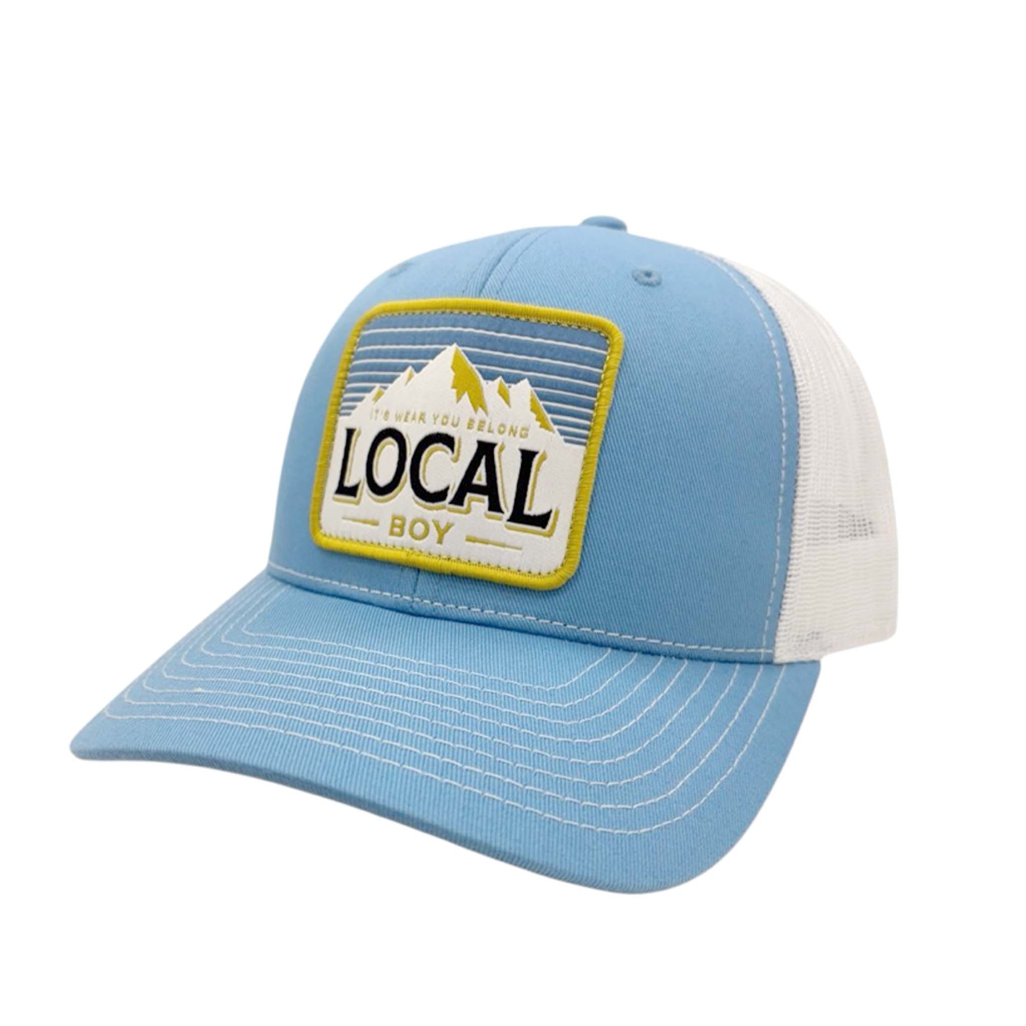 Local Boy Outfitters trucker hat in coastal blue with a mesh back and snapback closure, featuring a yellow and white embroidered patch that reads “Local Boy – It’s Where You Belong” with mountain design.