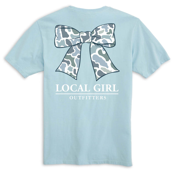 Local Girl Camo Bow Short Sleeve T-Shirt in chambray blue.  Featuring a large bow filled with gray and blue camo with Local Girl Outfitters logo below, this 100% cotton t-shirt is perfect for all-day comfort.
