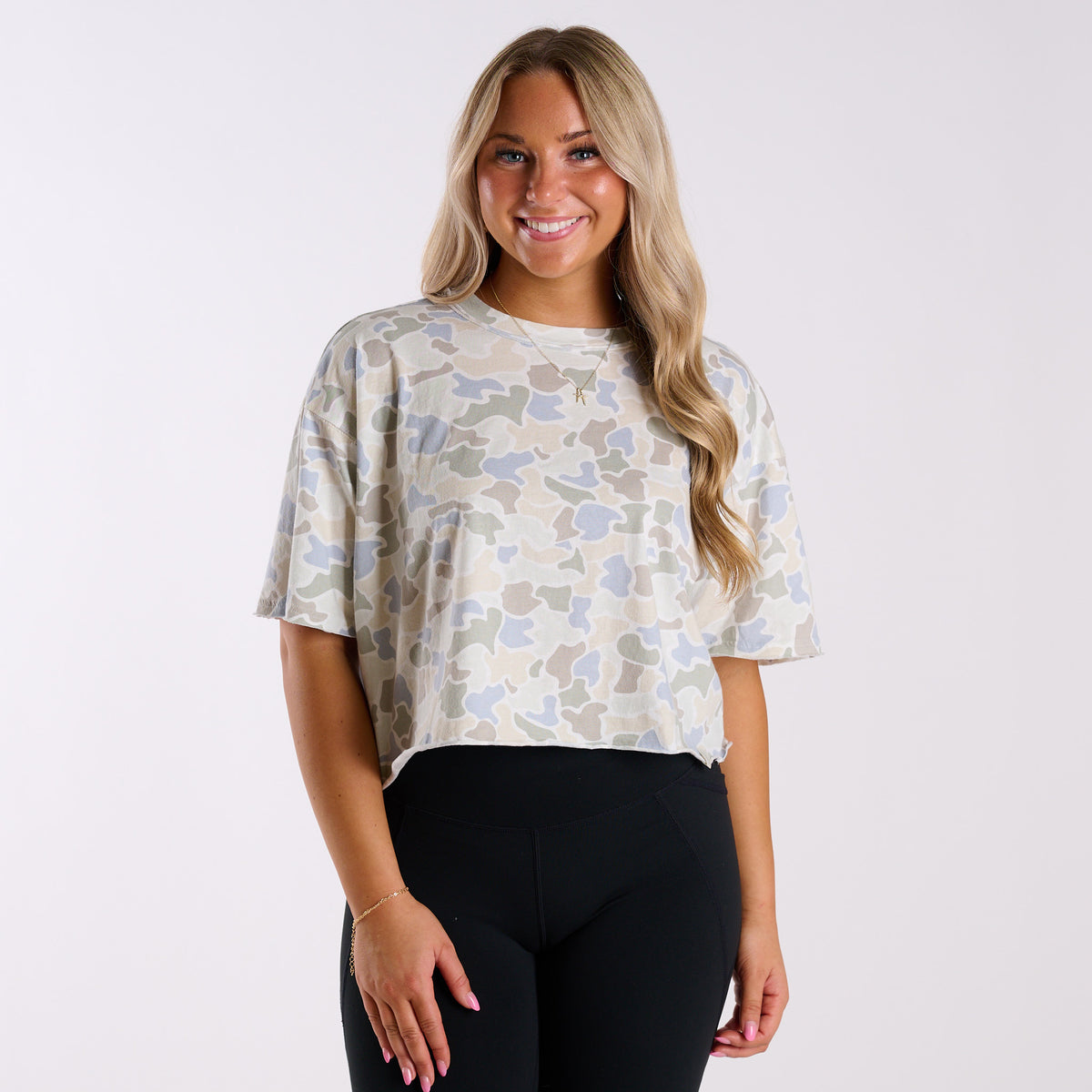 Woman wearing a white camo athletic top and black leggings.