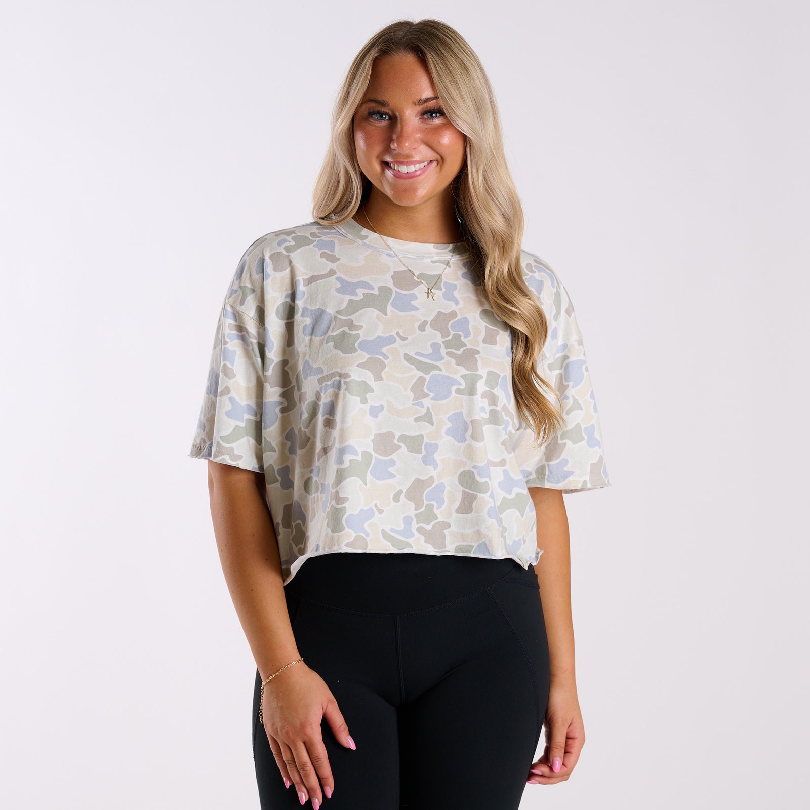 Woman wearing a white camo athletic top and black leggings.