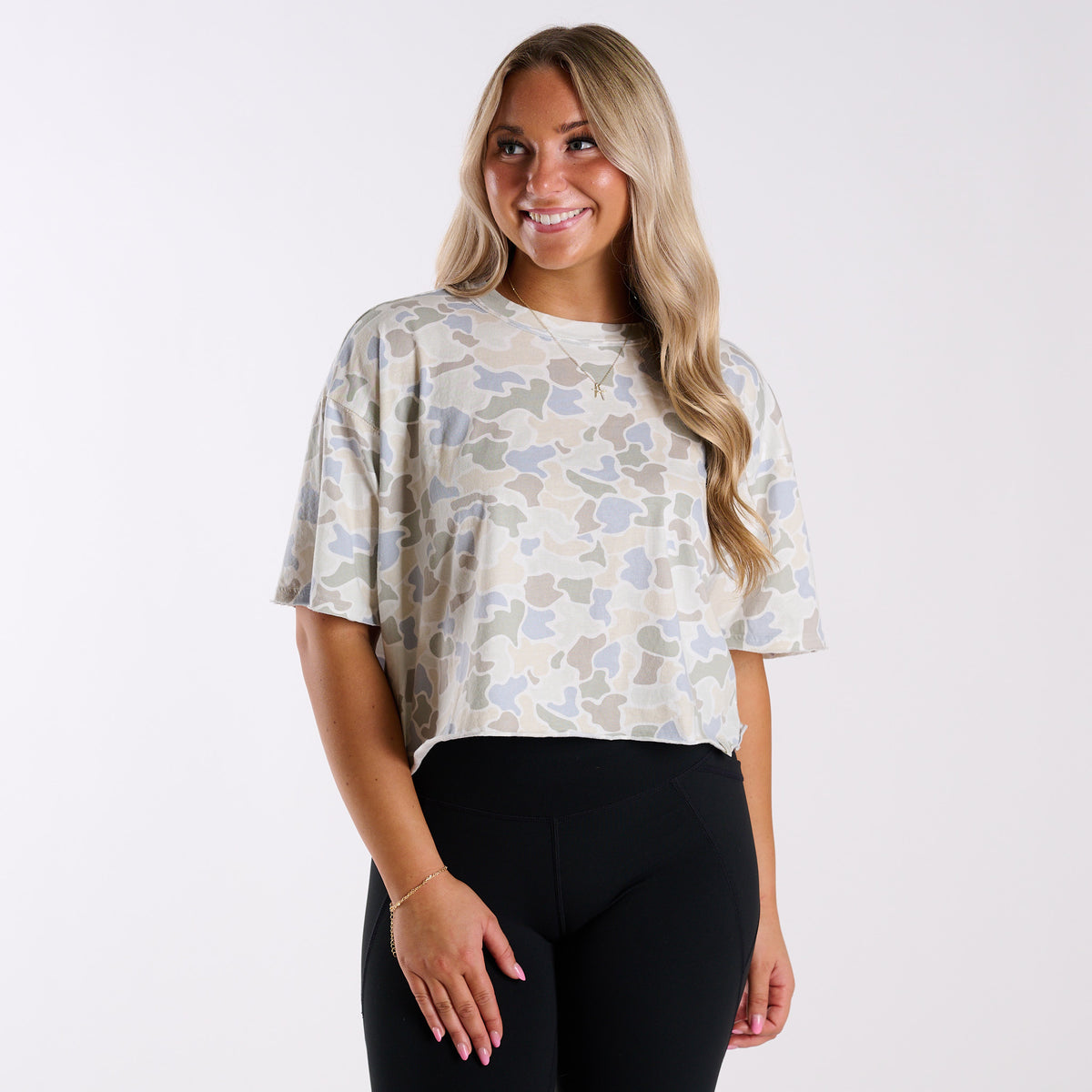 Woman wearing a white camo athletic top and black leggings.