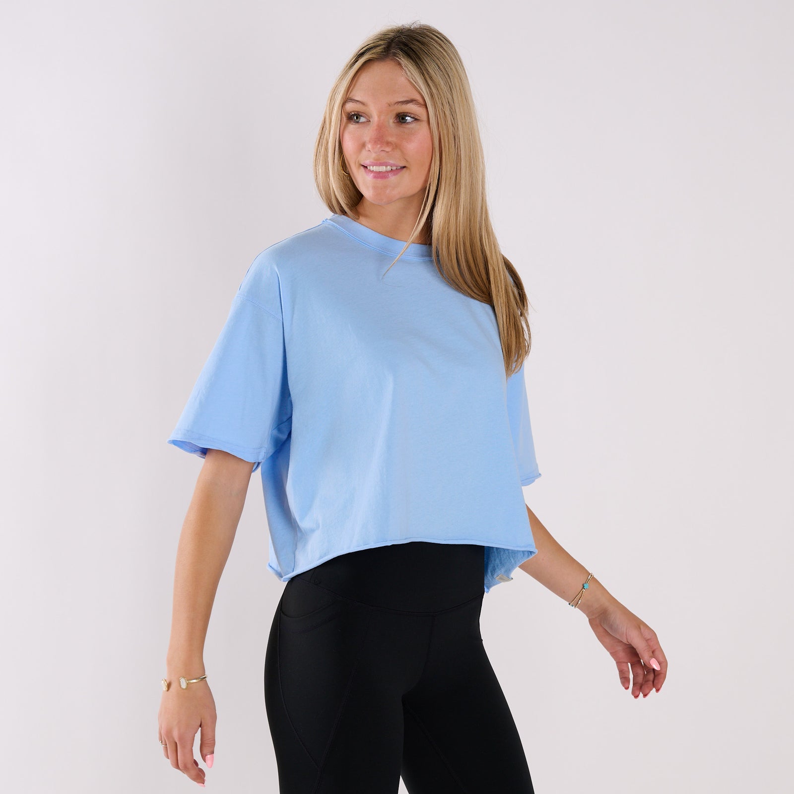 Woman wearing a light blue top and black leggings on a white background