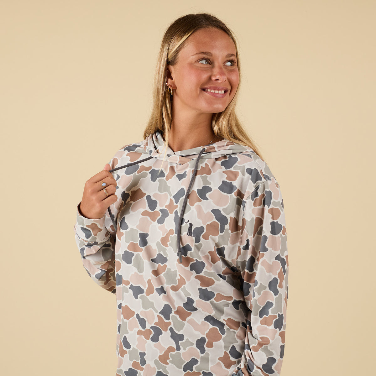 Side view of model adjusting drawstrings on camo flora performance hoodie.