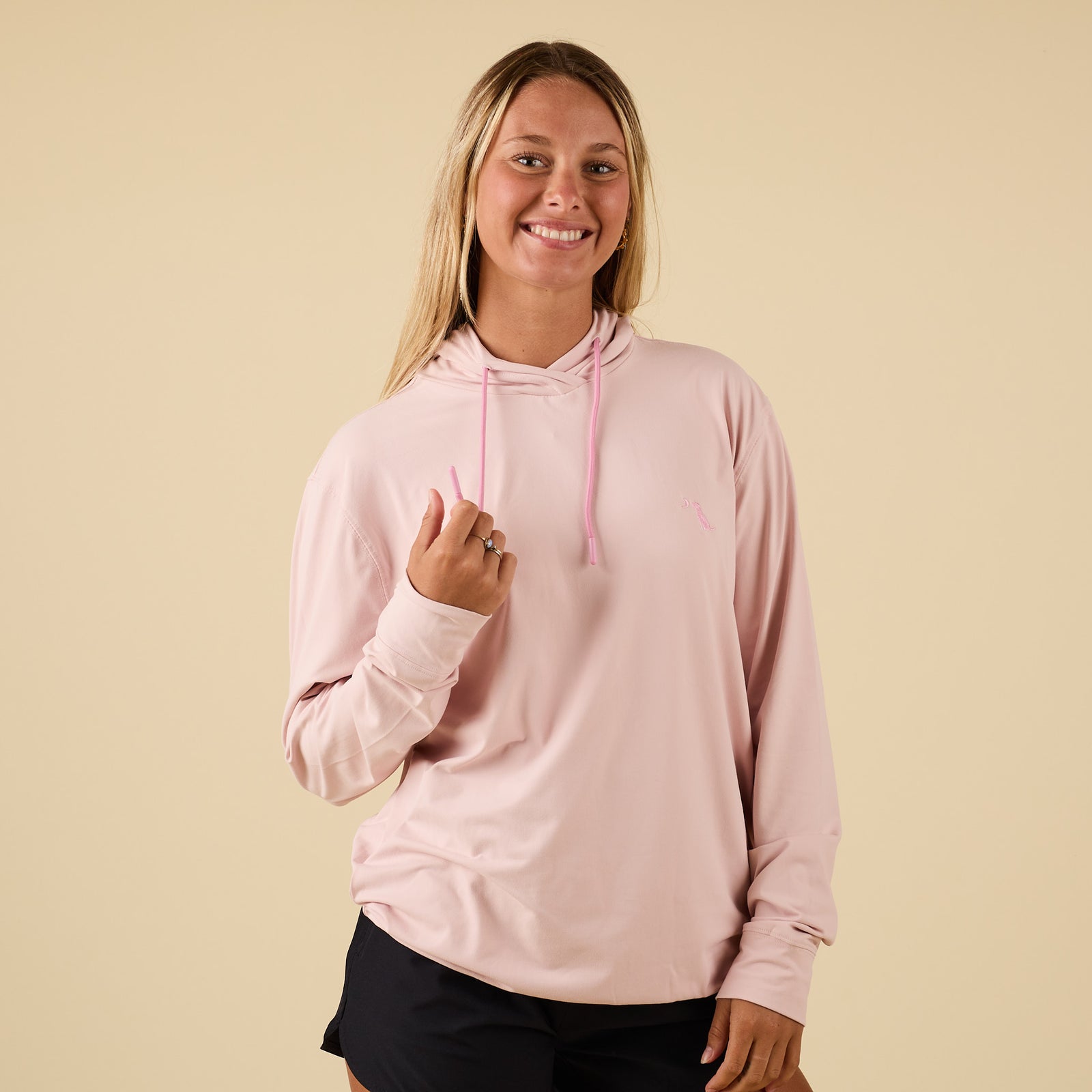 Front view of light pink performance hoodie with drawstrings and embroidered dog logo.