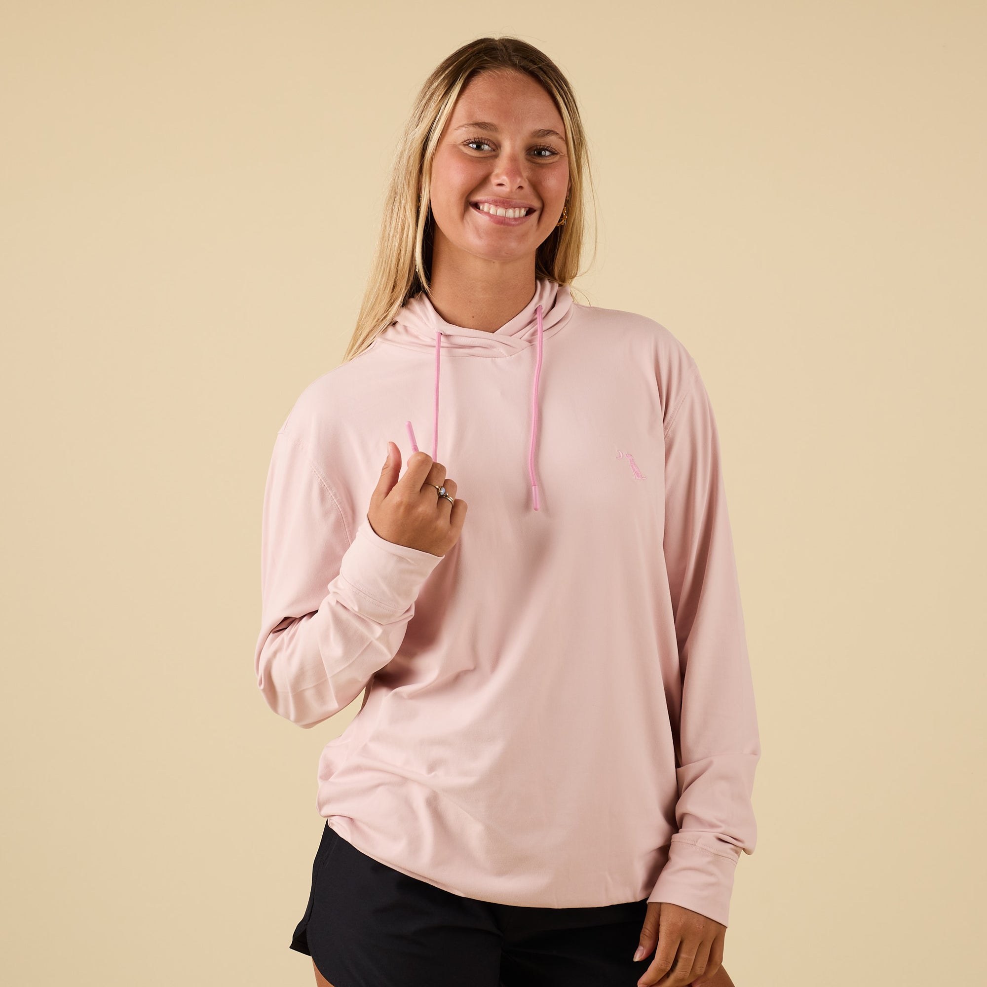 Front view of light pink performance hoodie with drawstrings and embroidered dog logo.