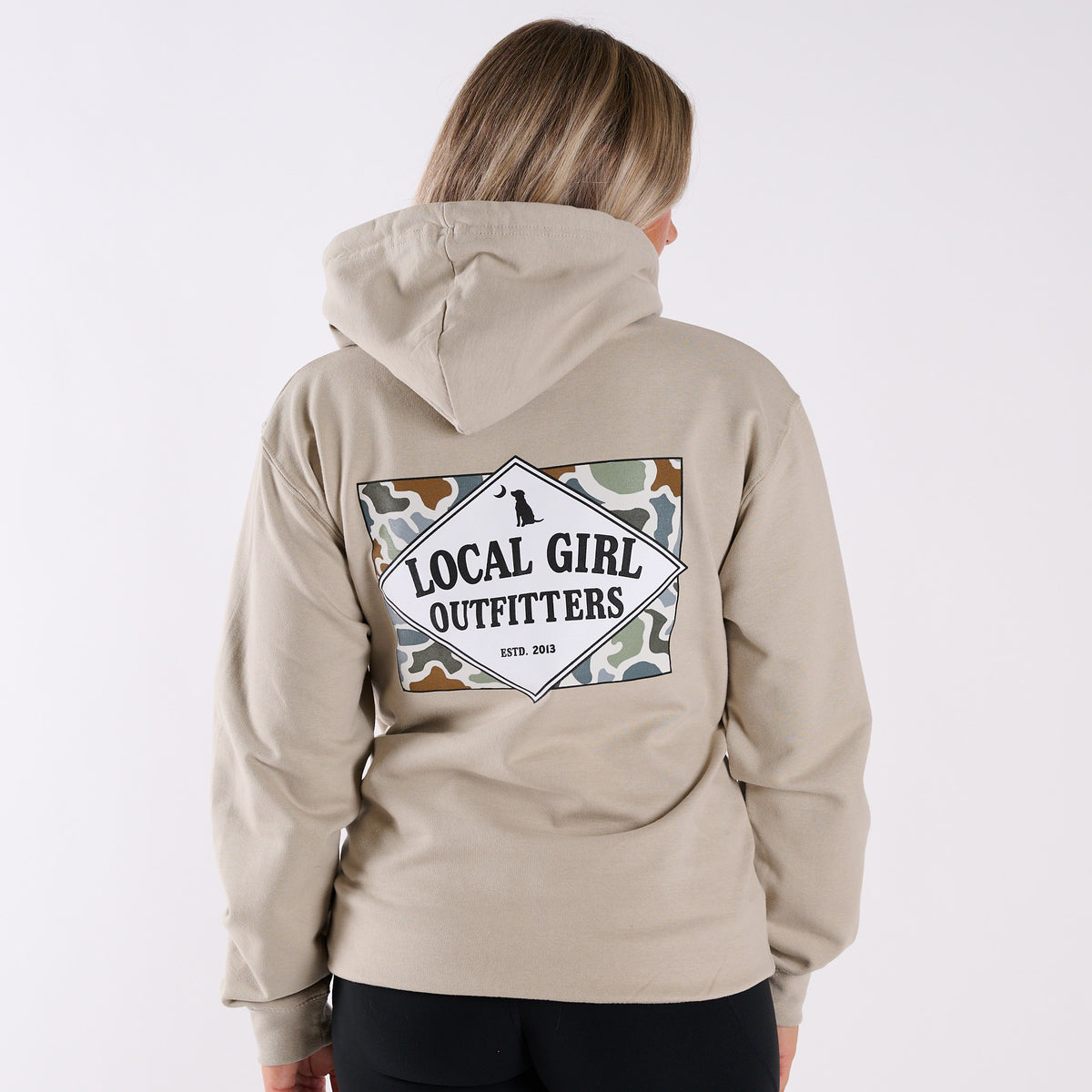 Person wearing a beige hoodie with 'Local Girl Outfitters' logo on the back against a white background