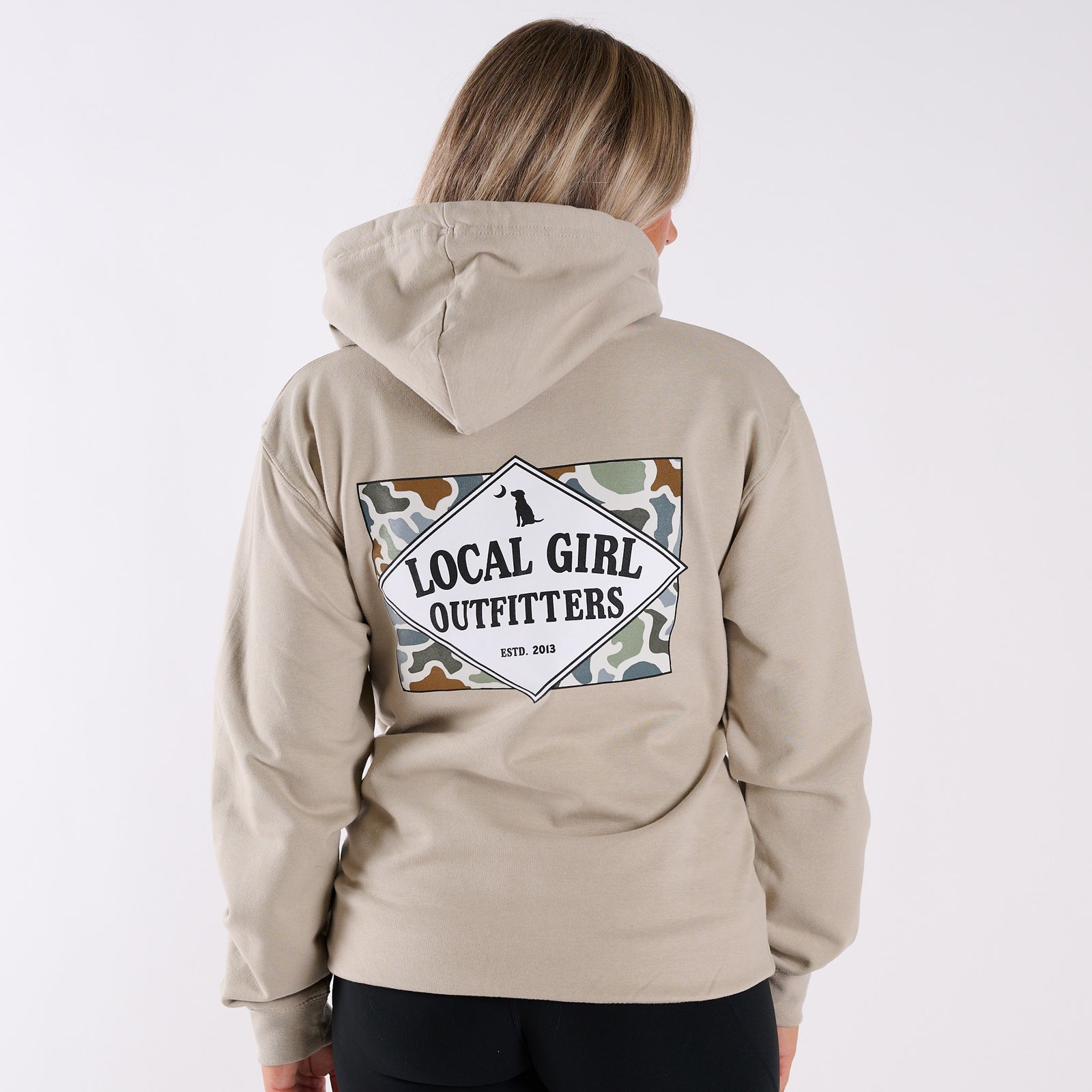 Person wearing a beige hoodie with 'Local Girl Outfitters' logo on the back against a white background